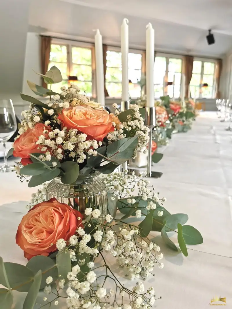 Pfirsichfarbene Rosen, Eukalyptus und Kerzen auf einer Hochzeitstafel