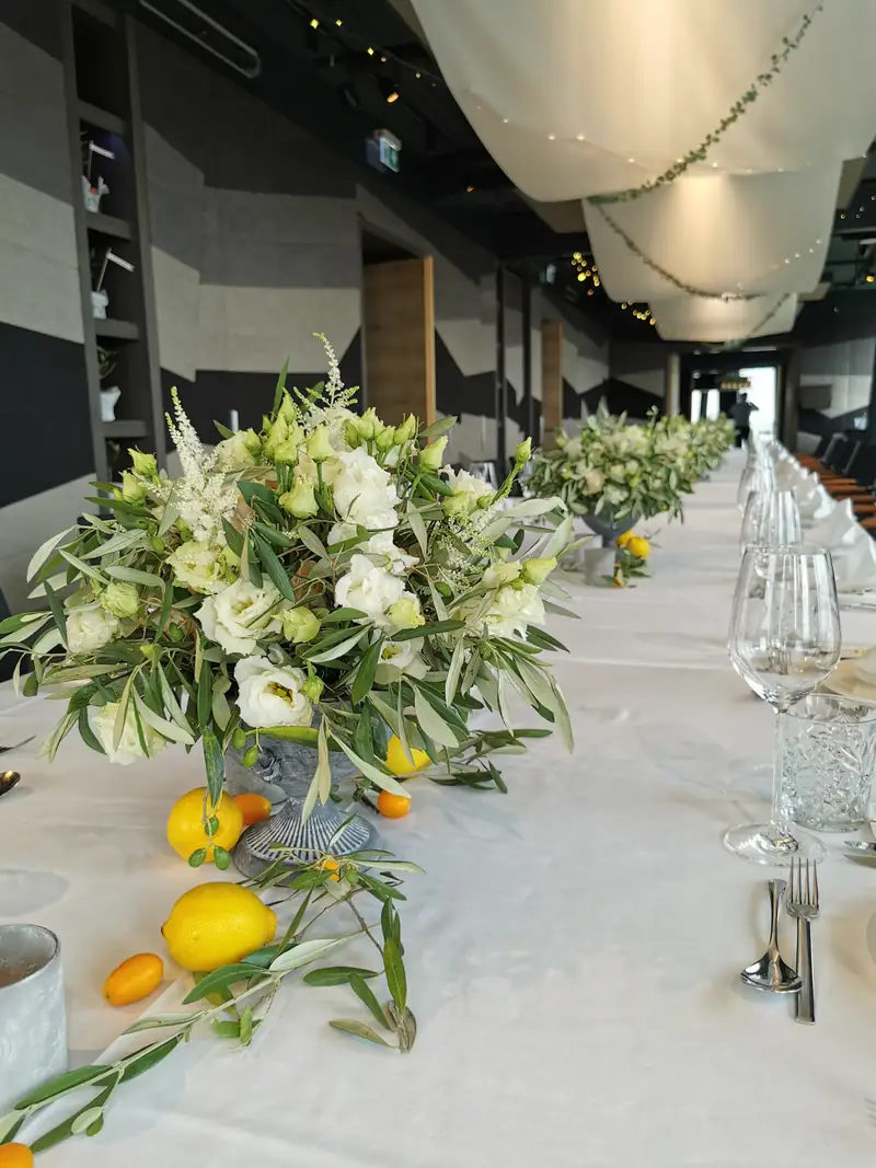 Lange Hochzeitstafel mit weißen Blüten, Olivenzweigen und Zitronen