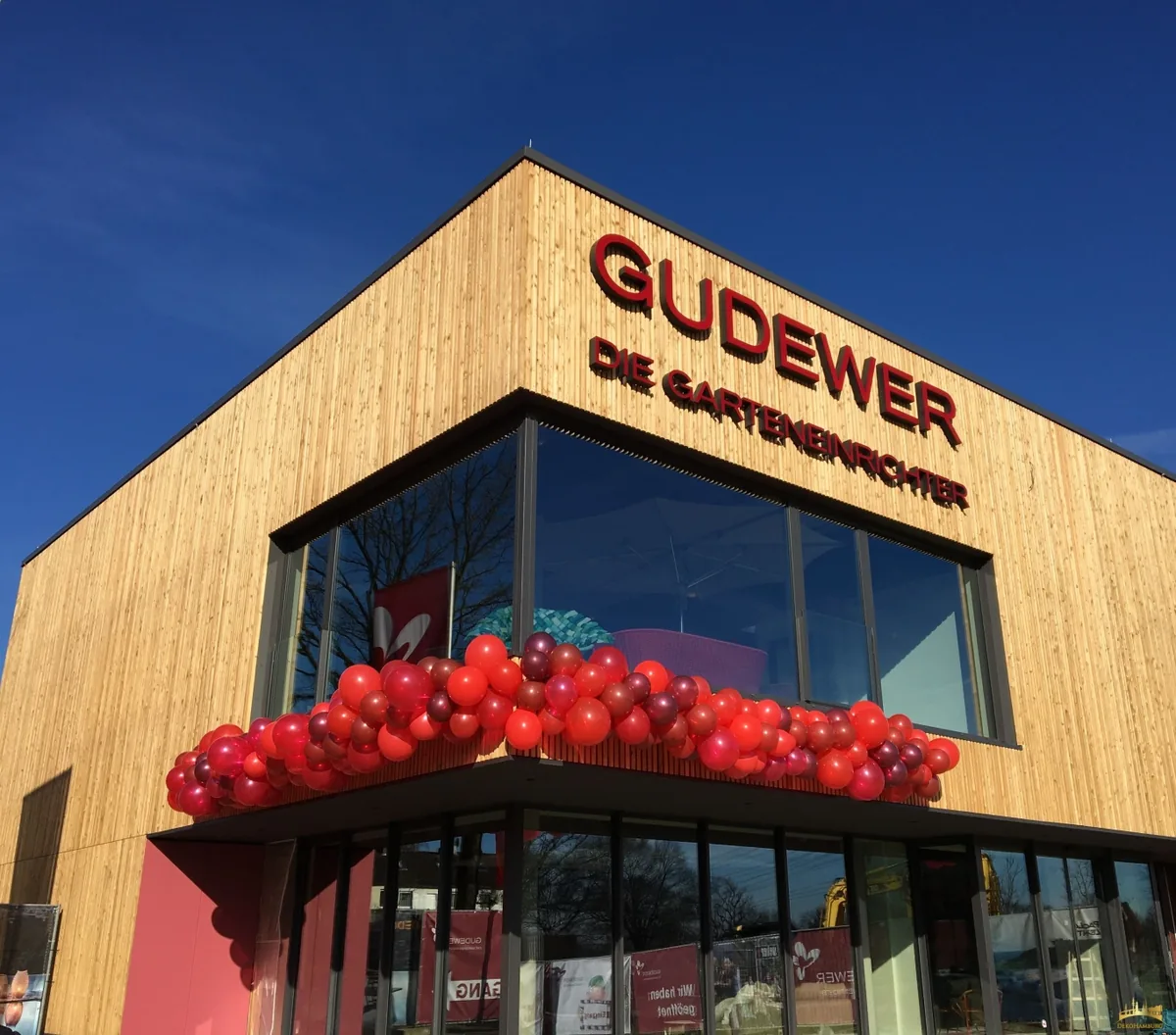 Rote organische Ballongirlande an einer Unternehmensfassade